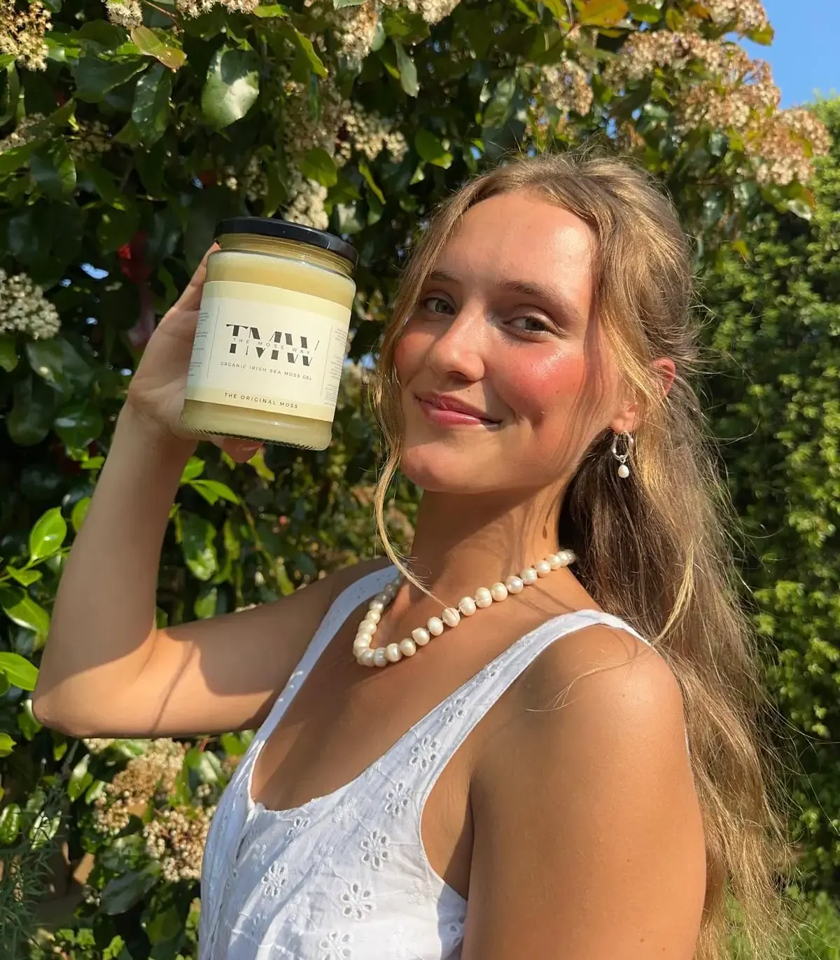 A real customer holding The Original Moss jar outside in the sun